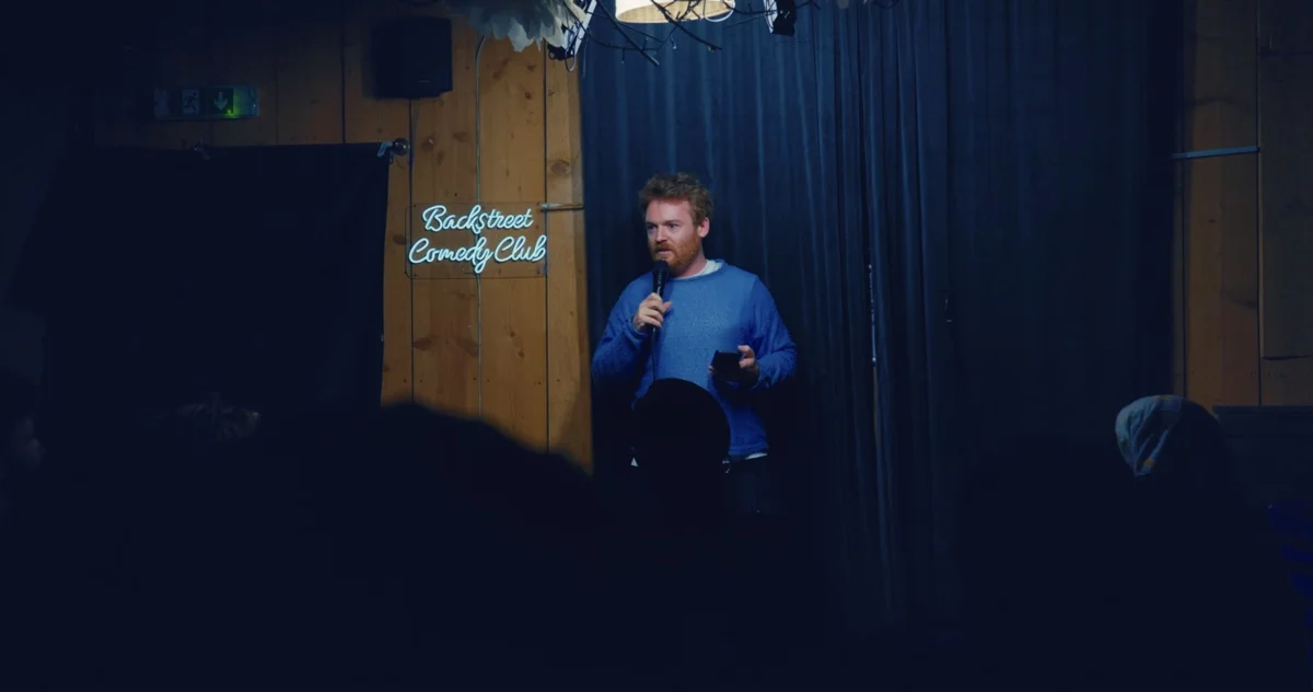 Wide filming angle showing the comedian, stage and audience at Backstreet Comedy Club